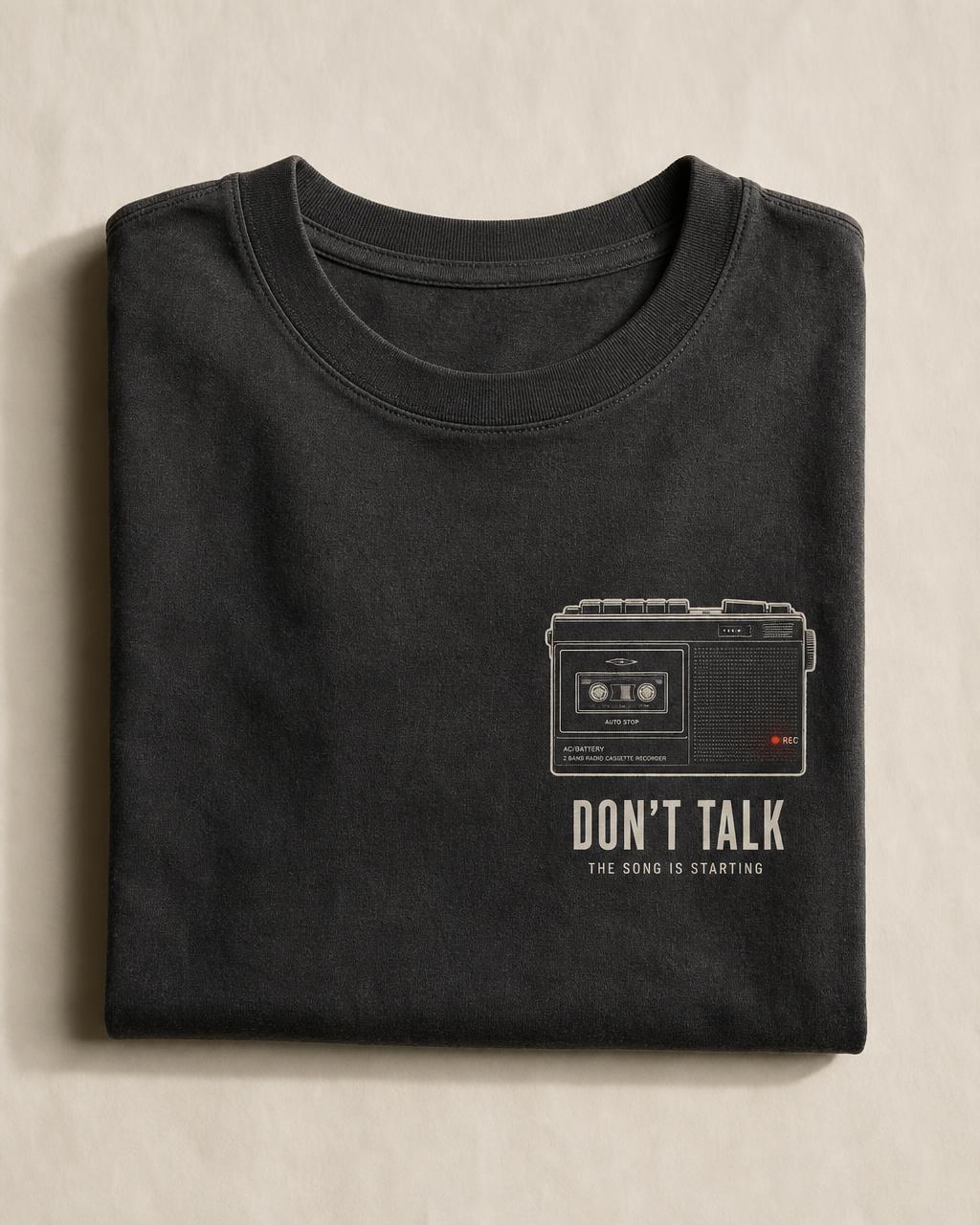 Folded charcoal t-shirt printed with a radio cassette recorder and the words Don't Talk